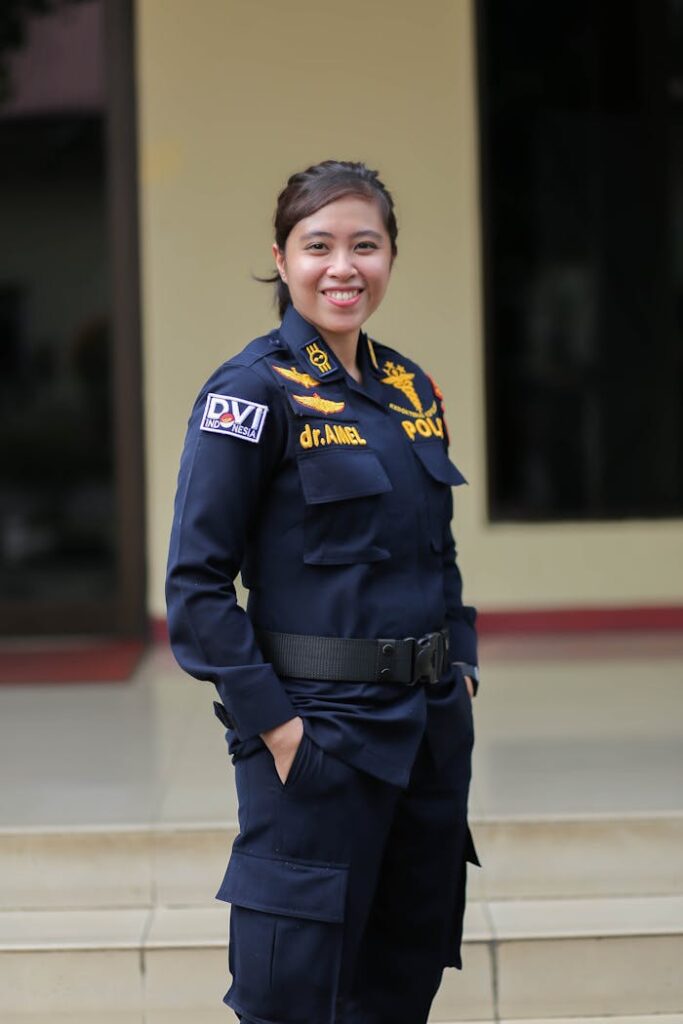 Asian female police officer smiling confidently while standing outdoors in Jakarta.